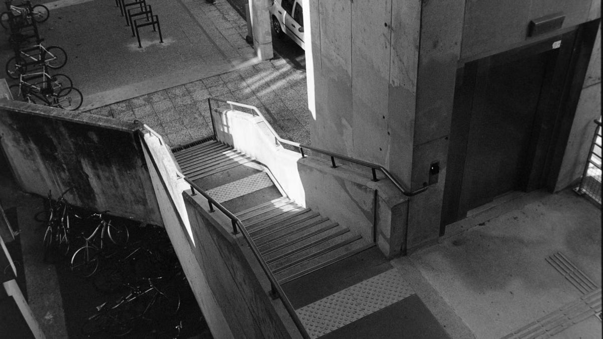 Black and white urban scene with concrete staircase and bicycles in Compiègne, France.